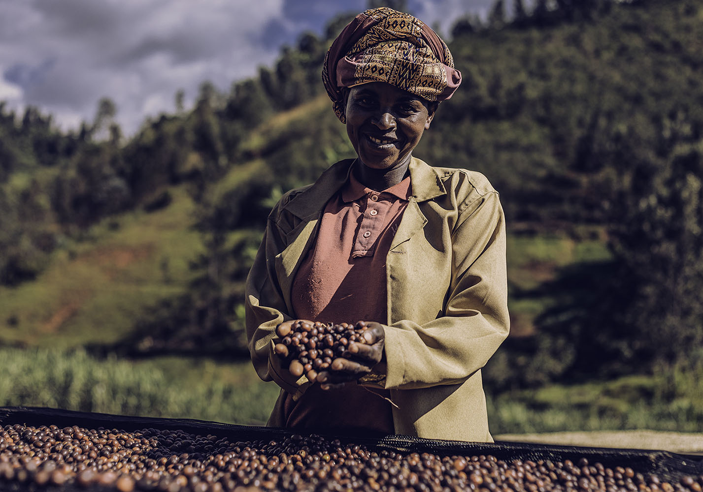 Staff holding coffee cherries drying on raised beds in Rwanda.